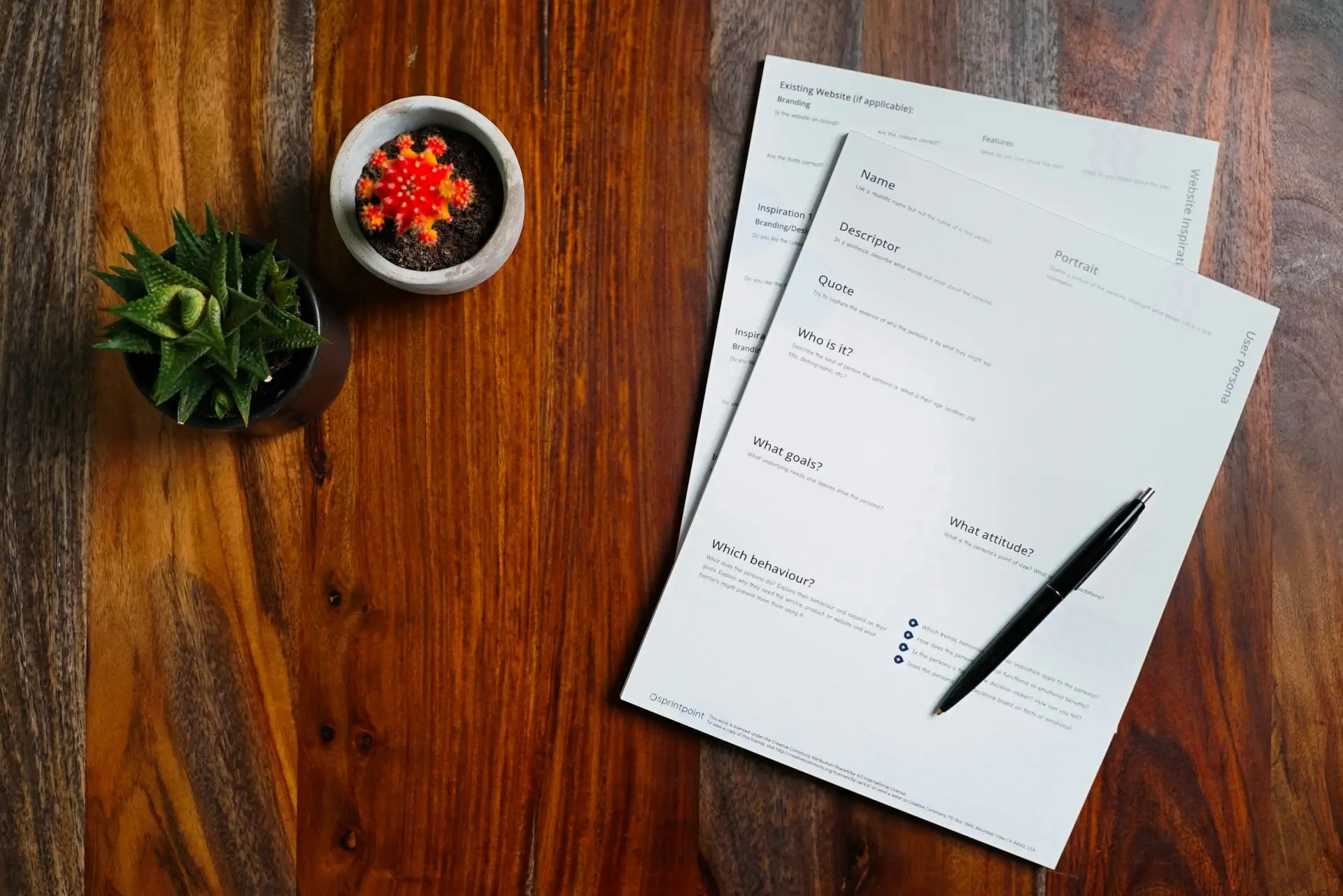 Printed paperwork and a pen resting on a dark wooden table